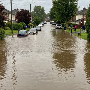 surburb flooded by rainwater to knee length with a few cars stuck in the road